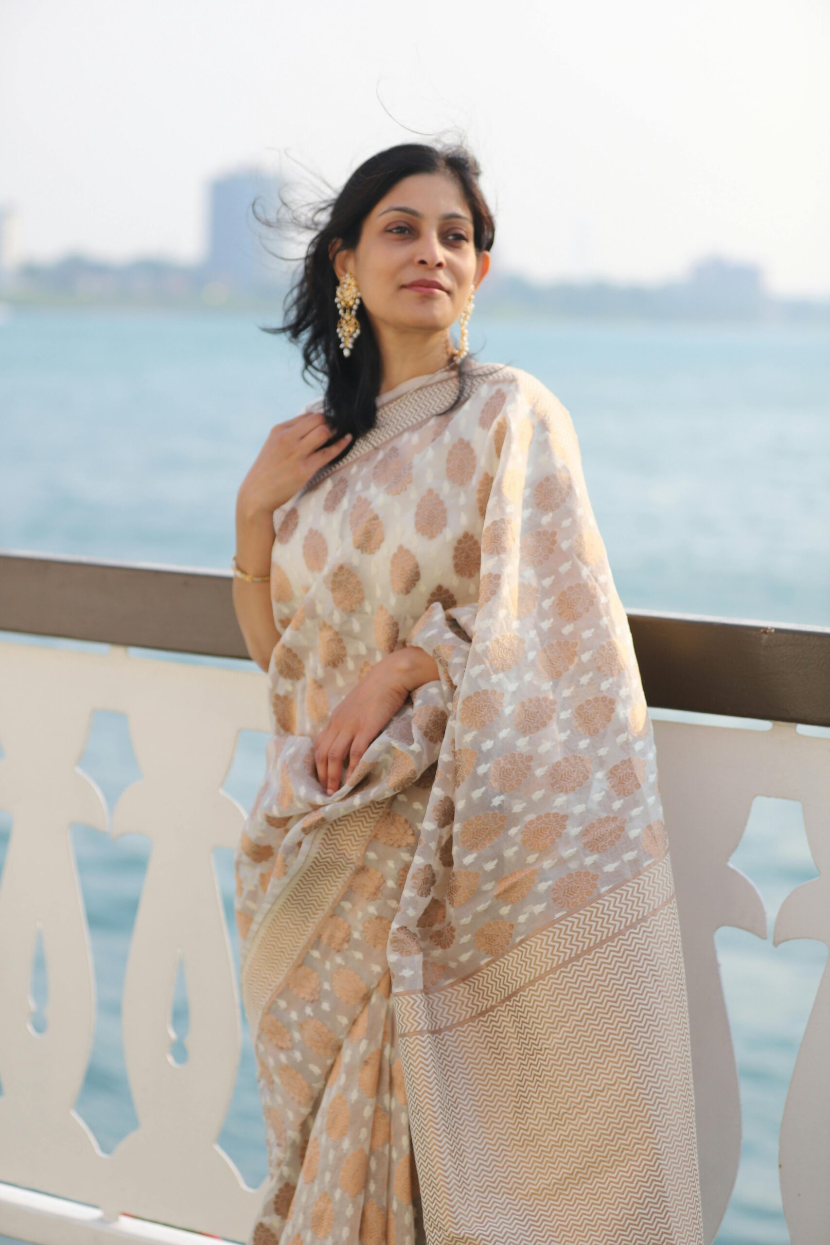 Portrait of a woman in a saree standing outdoors near the sea.